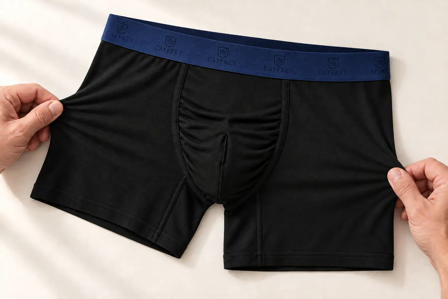 Hands gently stretching the black body fabric of Ballroom boxer briefs