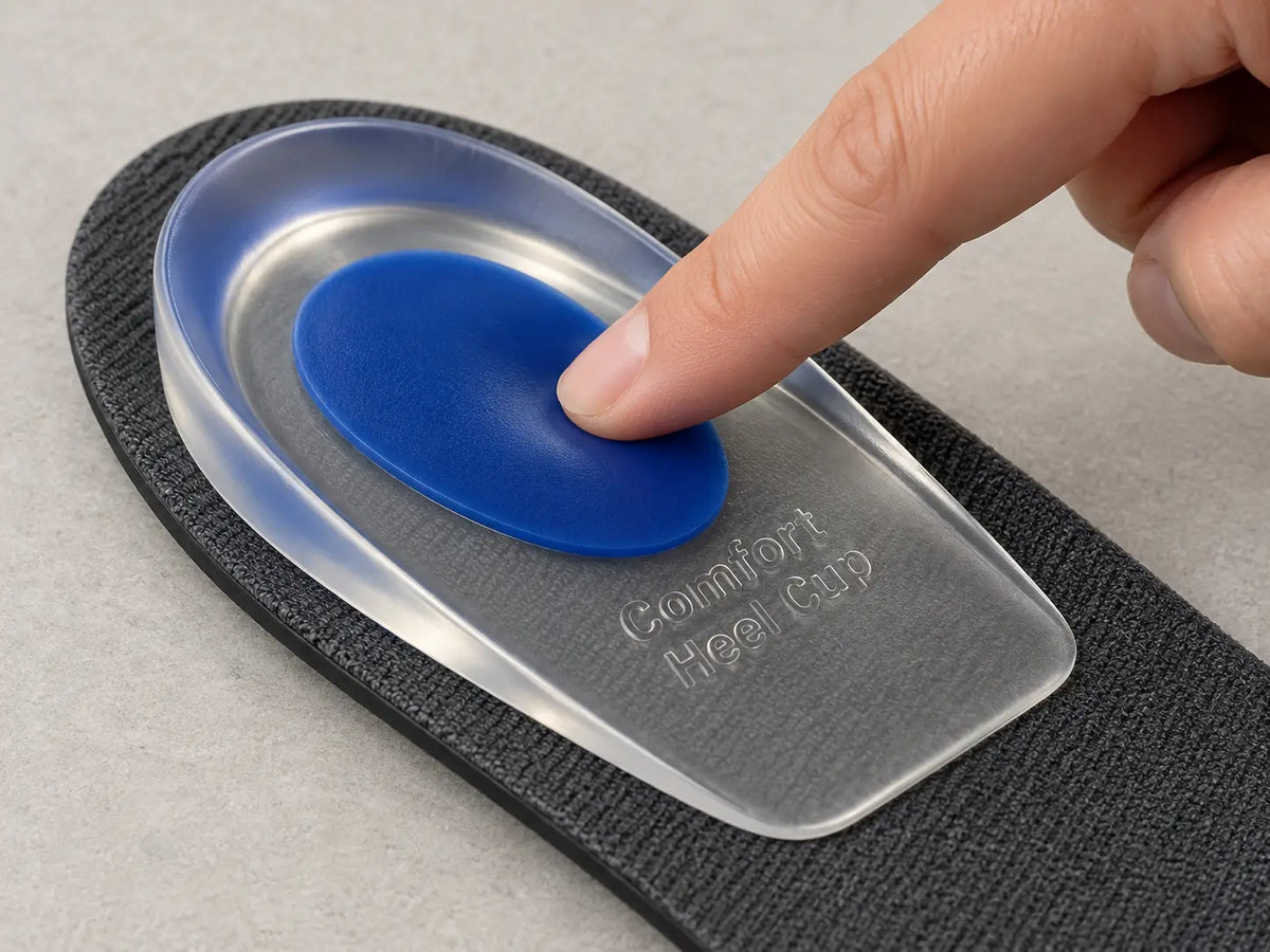 Detail illustration of a fingertip pressing the softer blue oval while the gel heel pad rests on an existing insole