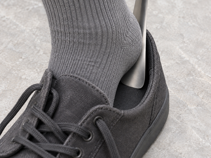 Use illustration: a grey-socked heel slides along the steel blade inside the same charcoal canvas shoe