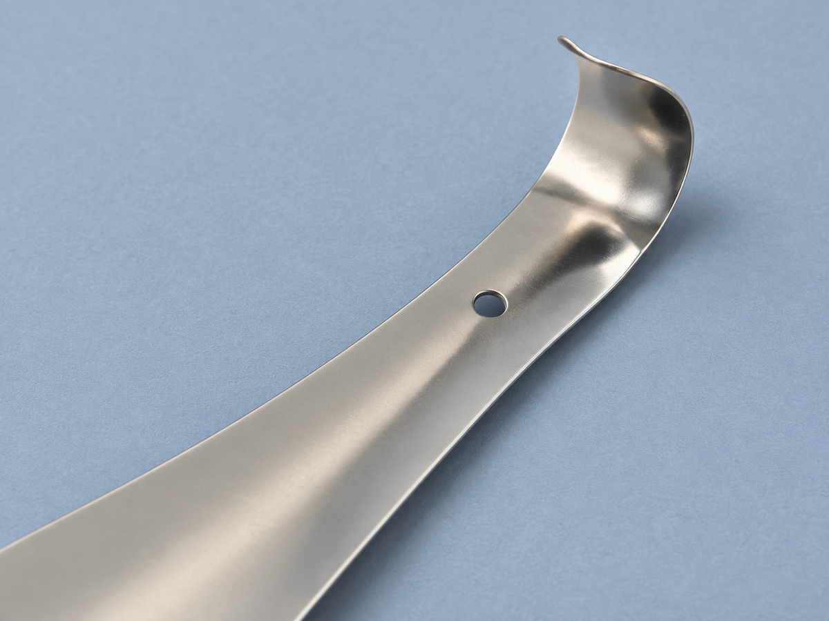 Close-up of the compact steel shoe horn showing its open turned grip and small circular hanging hole