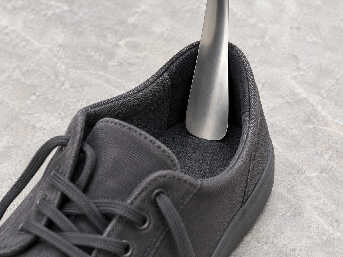 Placement illustration: the curved steel blade sits inside the heel collar of an open charcoal canvas shoe