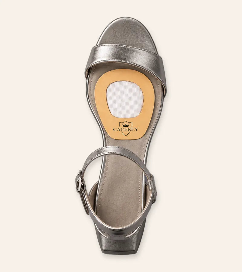 Illustration: overhead view of a silver sandal with a Crema Cortona pad on the footbed, wide end toward the toes