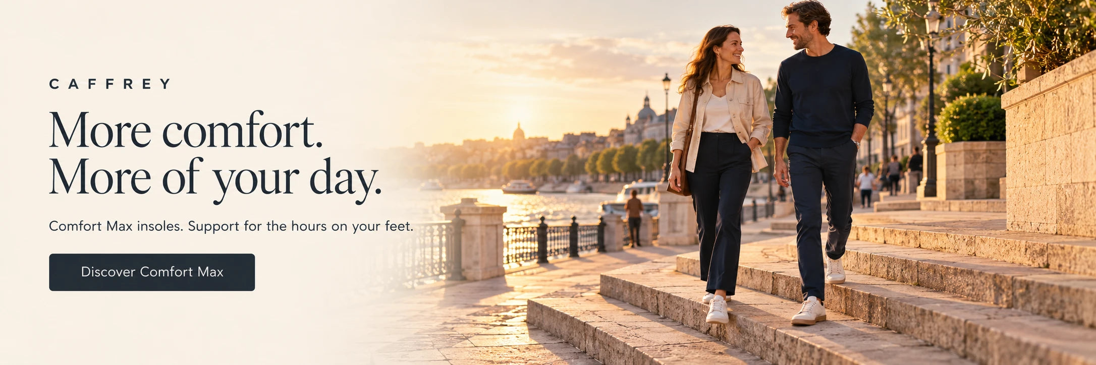 CAFFREY. More comfort. More of your day. Comfort Max insoles, support for the hours on your feet. A couple walking down sunlit waterfront steps.