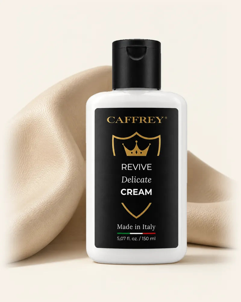 Illustration of the CAFFREY Revive Delicate Cream bottle standing in a soft fold of oat-coloured leather