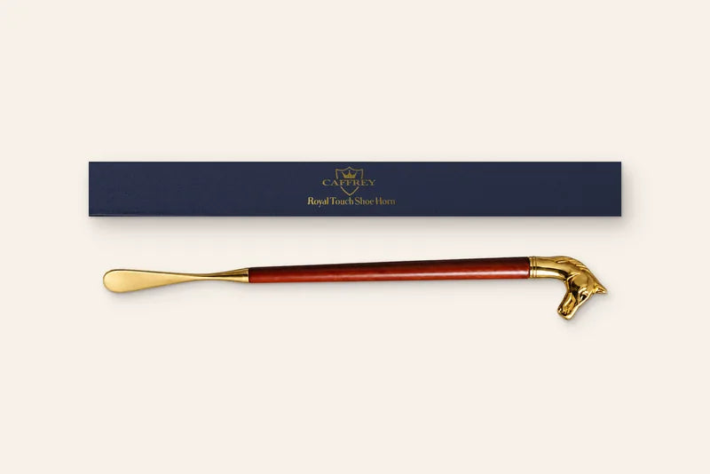 Composite of the navy CAFFREY Royal Touch gift box lid, its gold lettering, and the shoe horn laid beside it