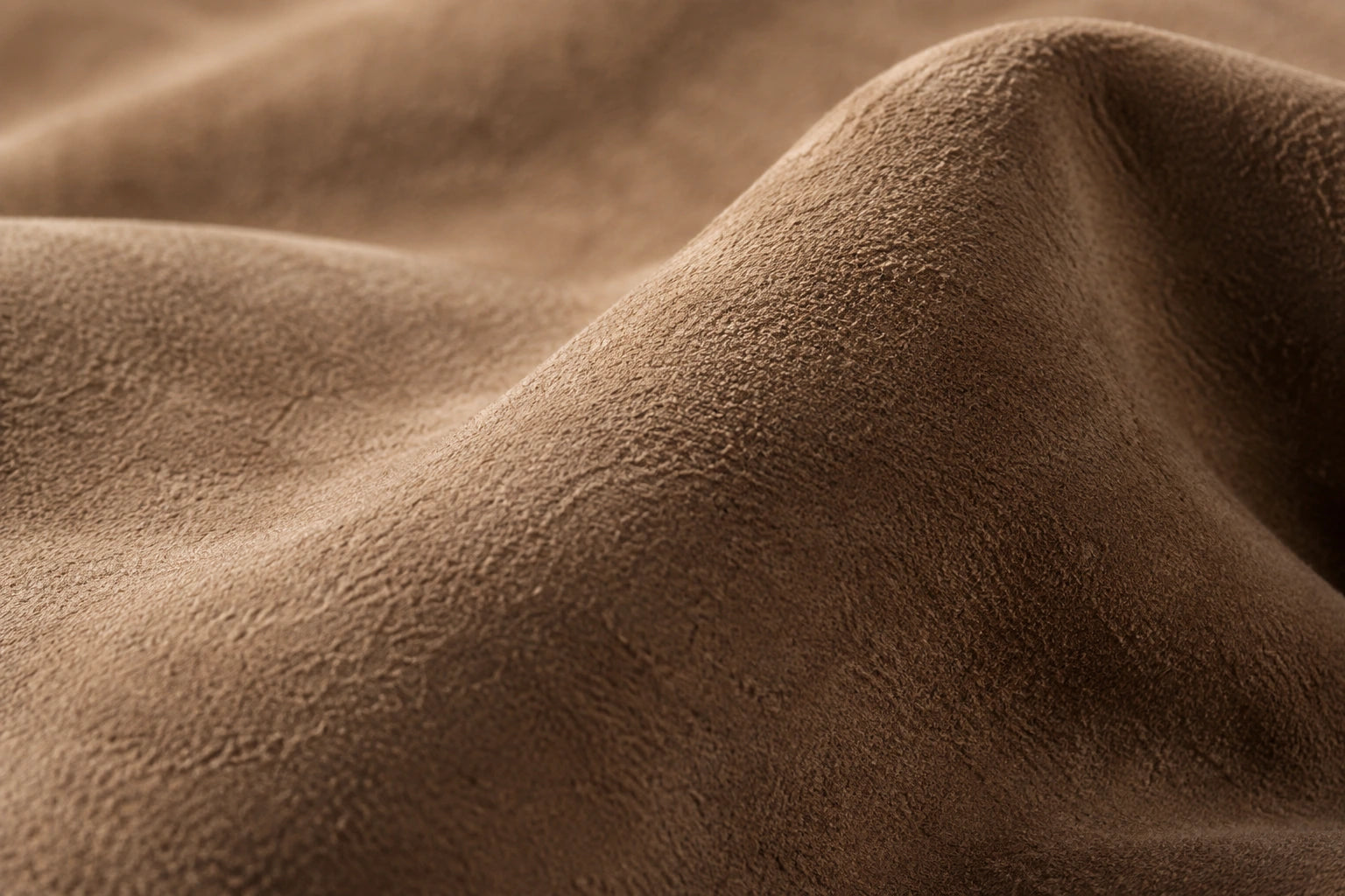 Editorial close-up of the soft, raised surface of brown suede leather