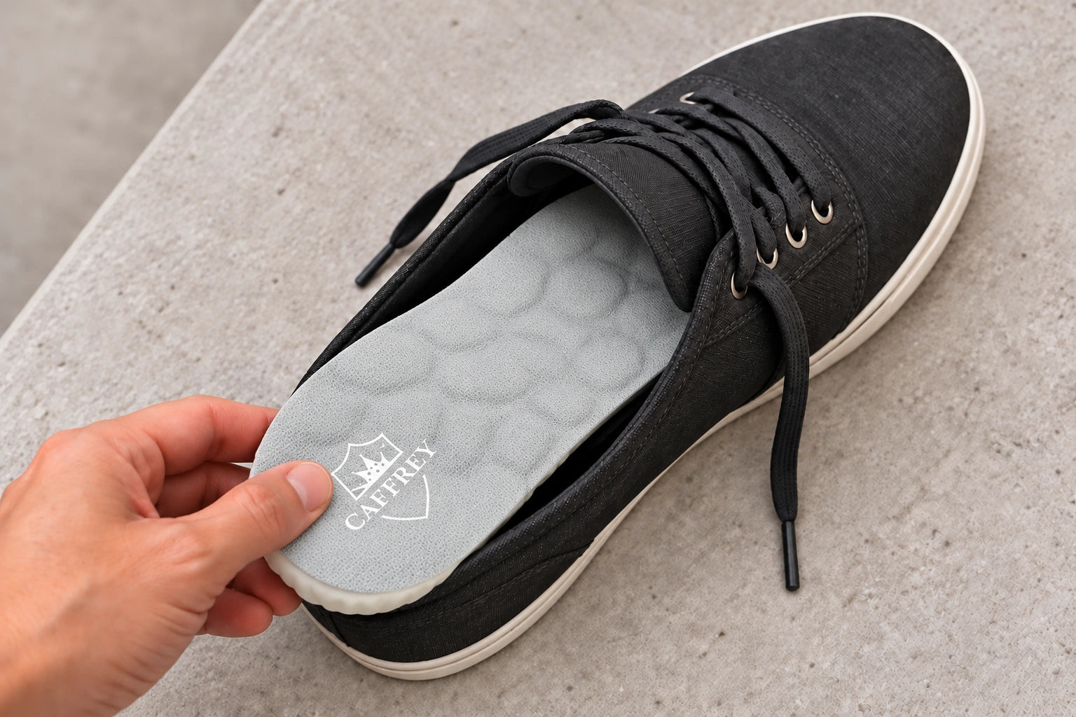 A hand seating the grey CAFFREY fabric side of Vital Step face up inside a charcoal lace-up shoe
