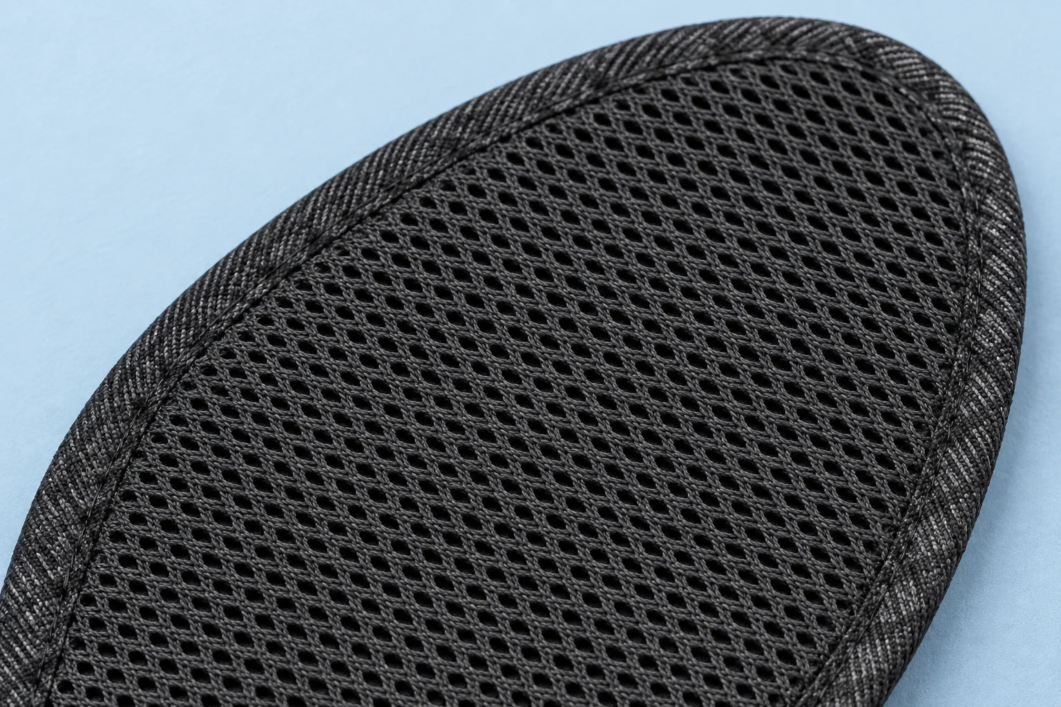 Reference-guided close-up of Zephyr’s black open textile mesh and narrow fabric-bound edge